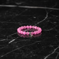 Pink beaded bracelet with a silver charm heart on a light fabric background