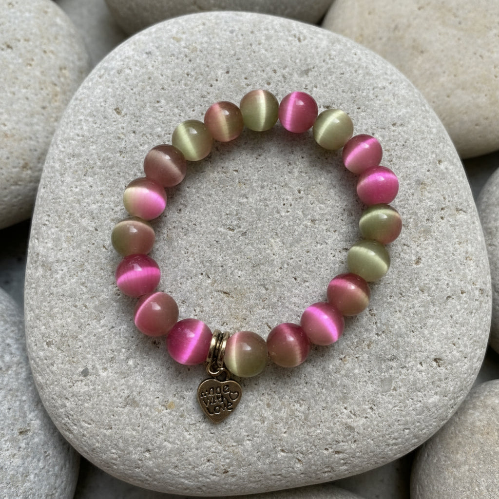 Multicolored beaded bracelet with a heart charm on a playful  background with confetti.
