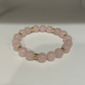 Pink beaded bracelet with gold accents on a white background