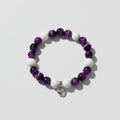 Bracelet with purple and white beads silver heart charm on a wooden surface