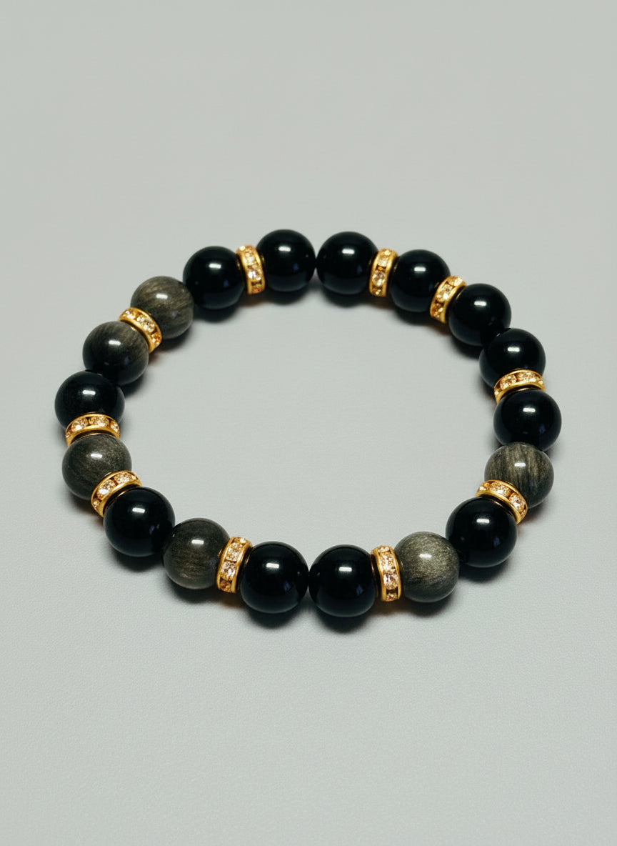 Black beaded bracelet with gold accents on a wooden surface