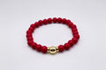 Red beaded bracelet with a gold accent on a white background