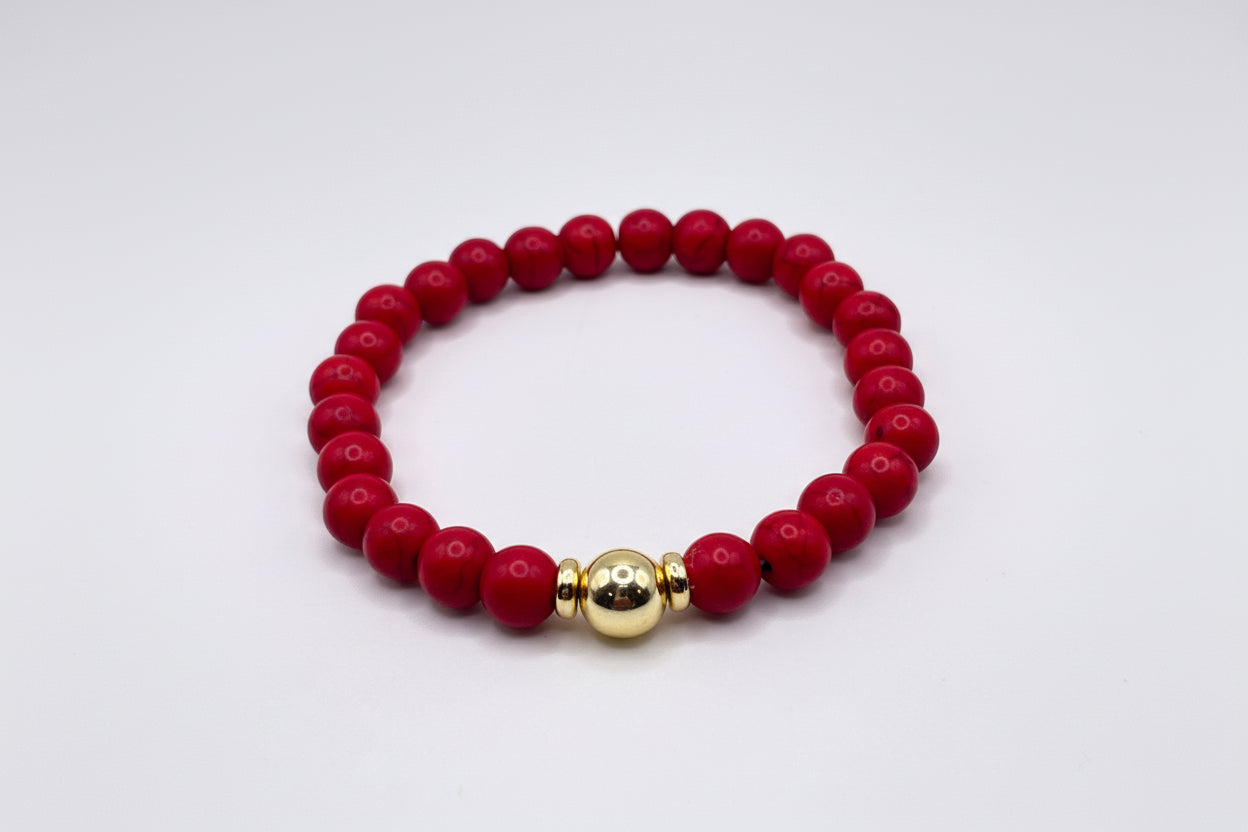 Red beaded bracelet with a gold accent on a white background