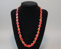 Necklace with red and gold beads on a black stand
