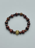 Bracelet with red tiger eye beads on a wooden surface