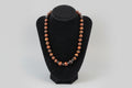 Necklace with red, brown and small black onyx beads spacers and hematite on a black stand