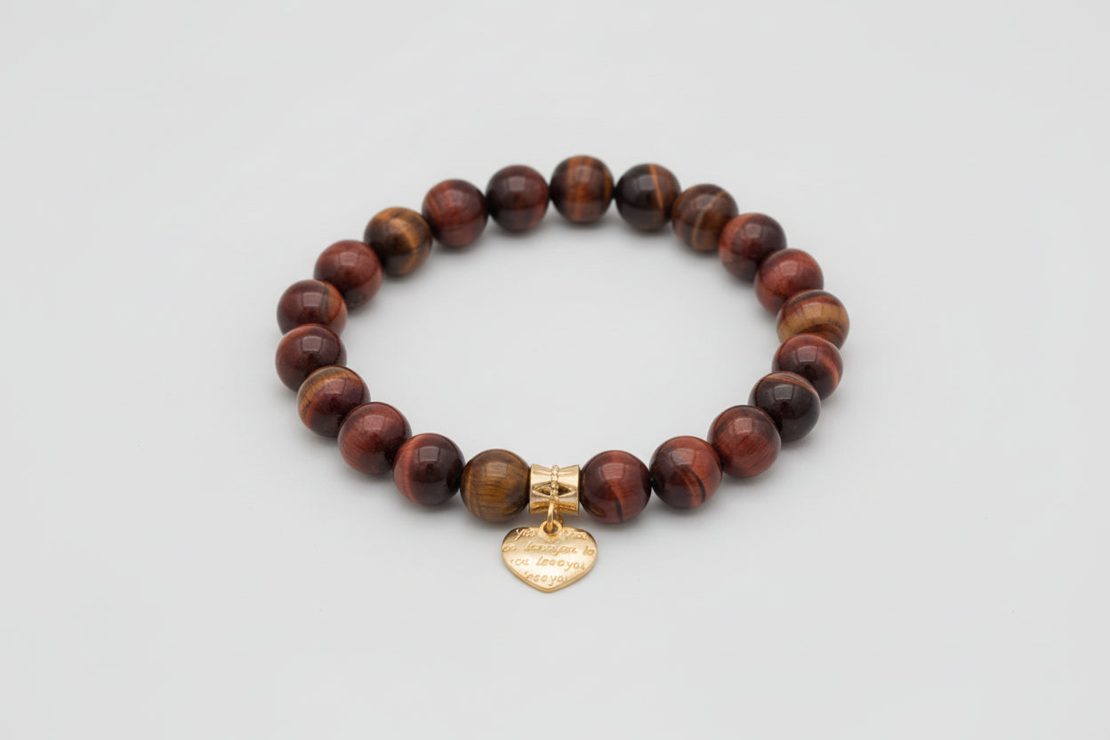 Bracelet with red tiger beads and a heart-shaped charm on a wooden surface