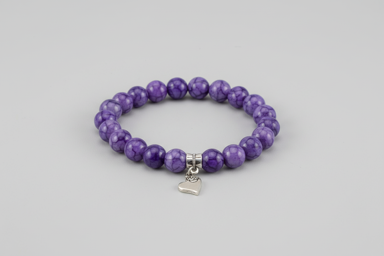 Purple beaded bracelet with a silver heart charm on a wooden surface
