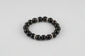 Black beaded bracelet with rose gold accents on a wooden surface