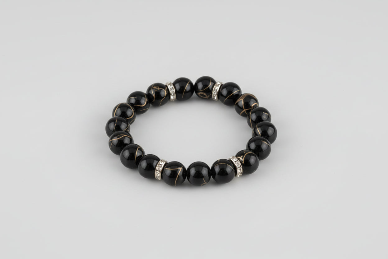 Black beaded bracelet with rose gold accents on a wooden surface