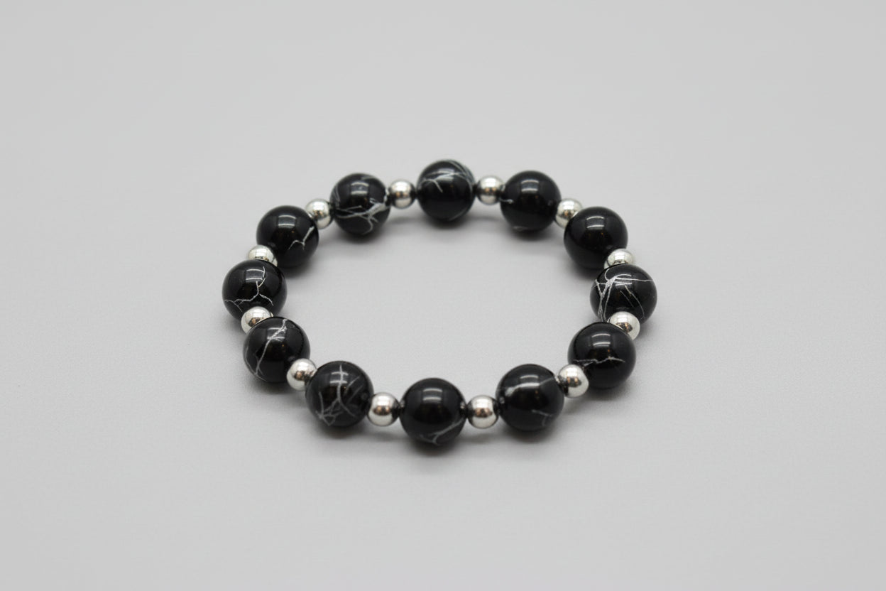 Black beaded bracelet with silver accents on a wooden surface