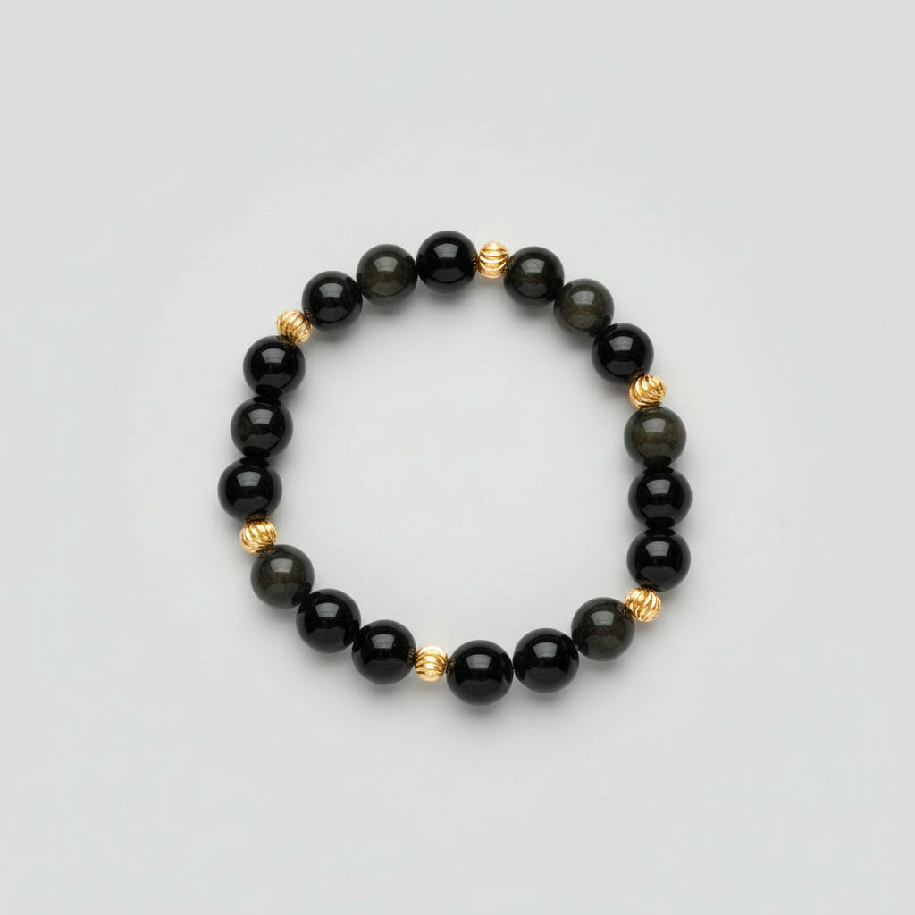 Black and beaded bracelet with gold accents on a wooden surface