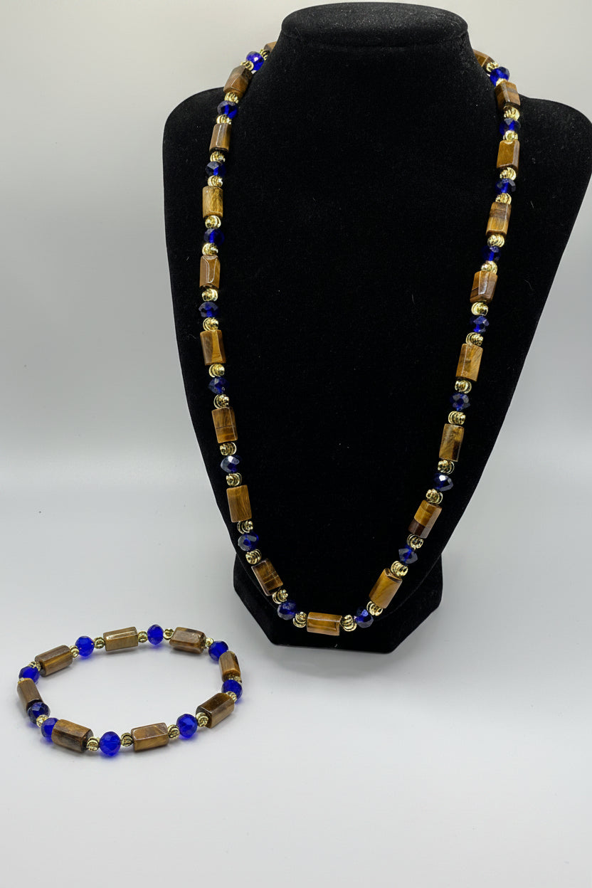 Beaded necklace with blue and gold beads on a black stand and white background