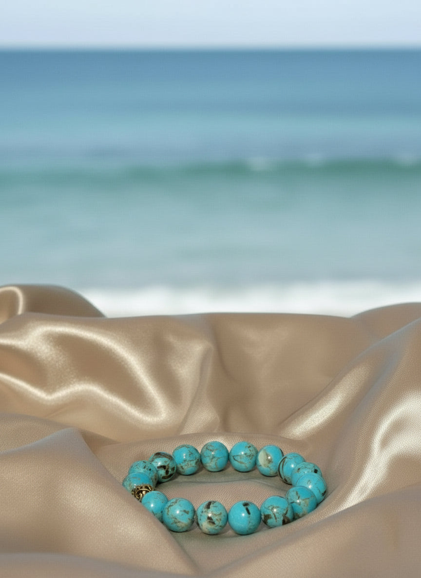 Blue Turquoise beaded bracelet with silver spacer accents on a beige fabric background