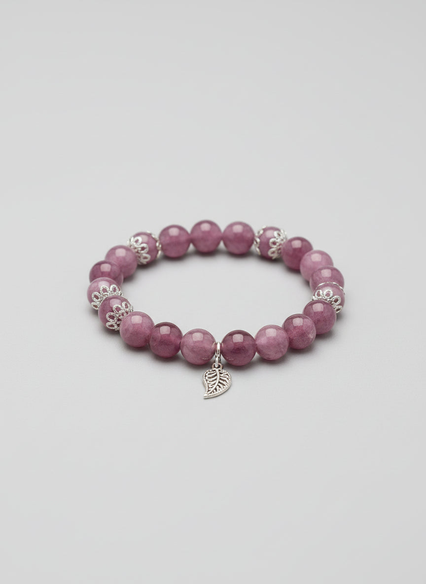 Purple beaded bracelet with silver charms on a wooden surface