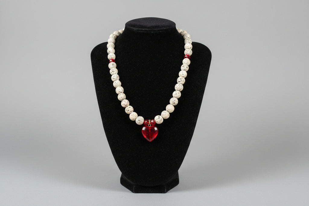 Beaded bracelet with a red charm on a black stand against a blurred kitchen background