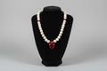 Beaded bracelet with a red charm on a black stand against a blurred kitchen background