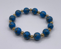 Blue beaded bracelet with gold accents on a light gray background