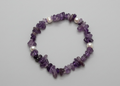 Purple beaded bracelet with pearls on a gray background