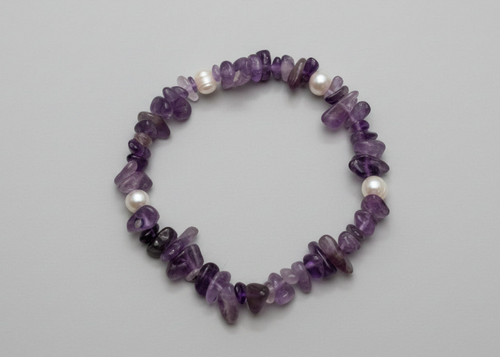 Purple beaded bracelet with pearls on a gray background