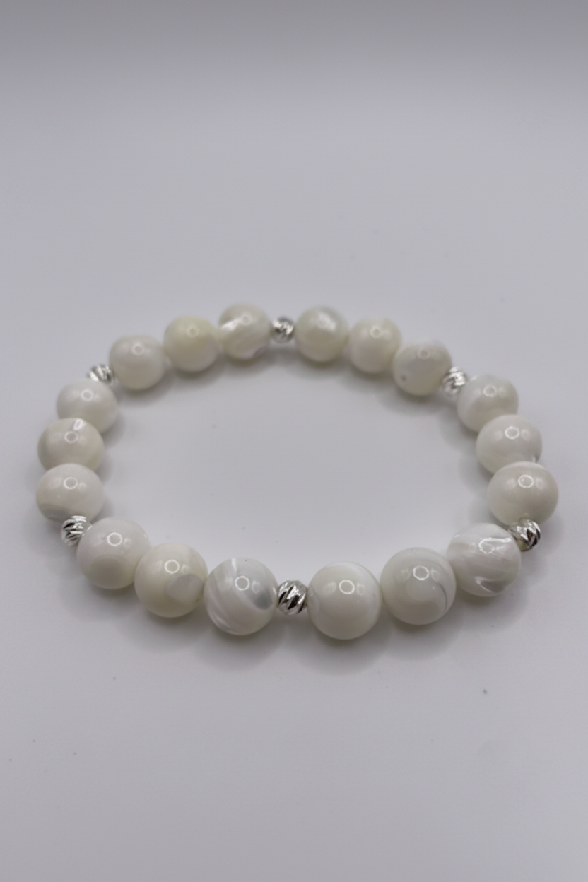 White beaded bracelet with silver accents on a light gray background