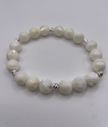 White beaded bracelet with silver accents on a light gray background