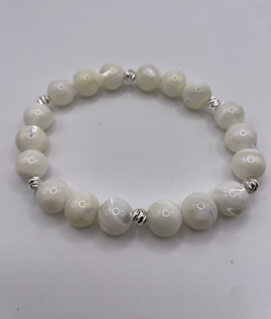 White beaded bracelet with silver accents on a light gray background