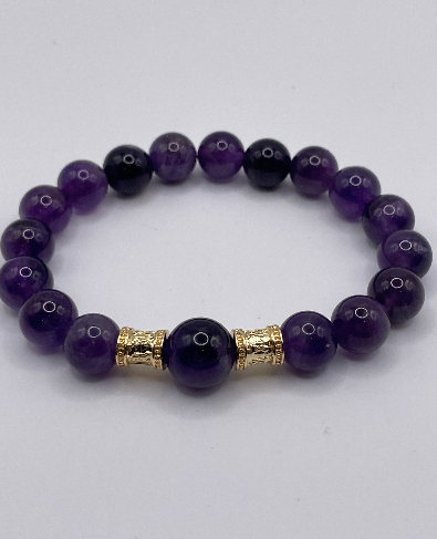 Purple beaded bracelet with a gold accent on a white background