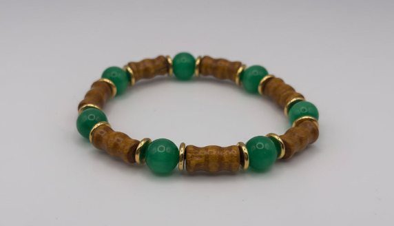 Bracelet with green beads and wooden accents on a light gray background