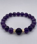 Purple beaded bracelet with gold accents on a white background