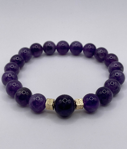 Purple beaded bracelet with gold accents on a white background