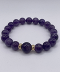 Purple beaded bracelet with a gold accent on a white background