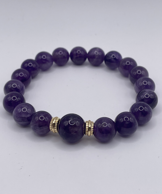 Purple beaded bracelet with a gold accent on a white background