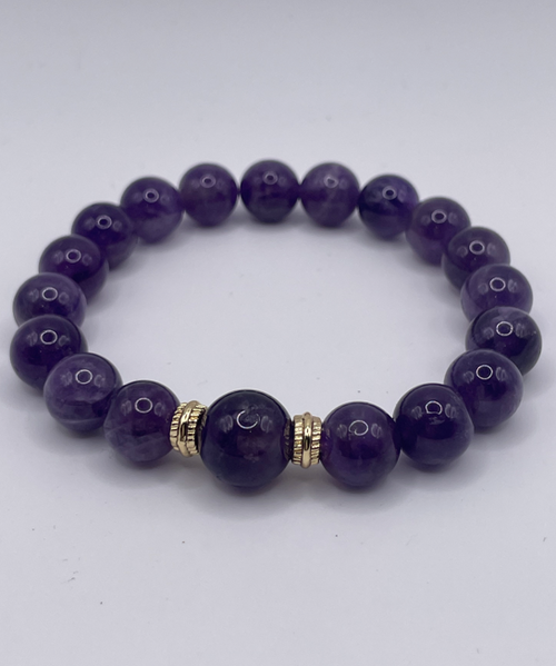 Purple beaded bracelet with a gold accent on a white background